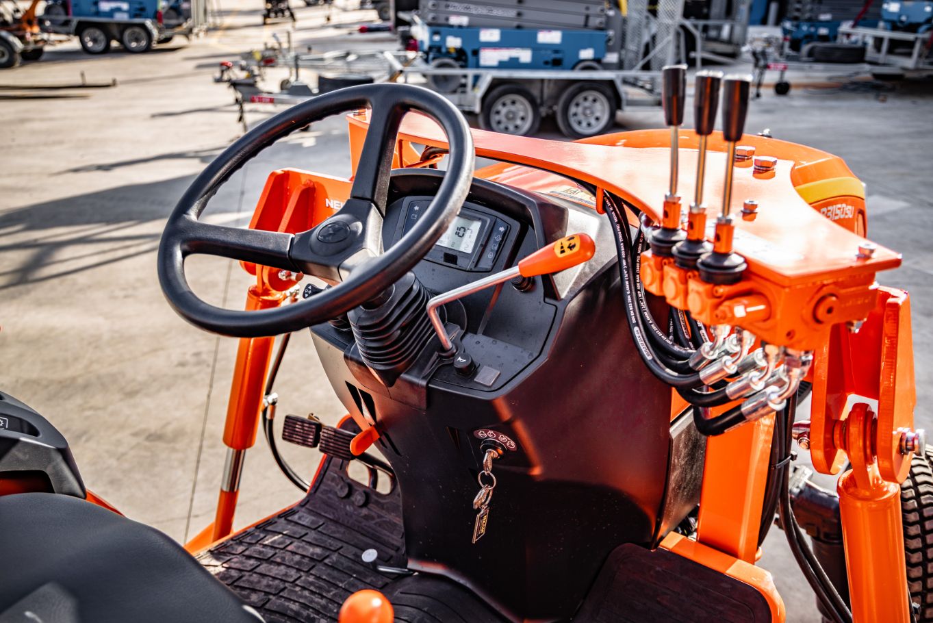 Inside tractor view of black steering wheel with orange interior