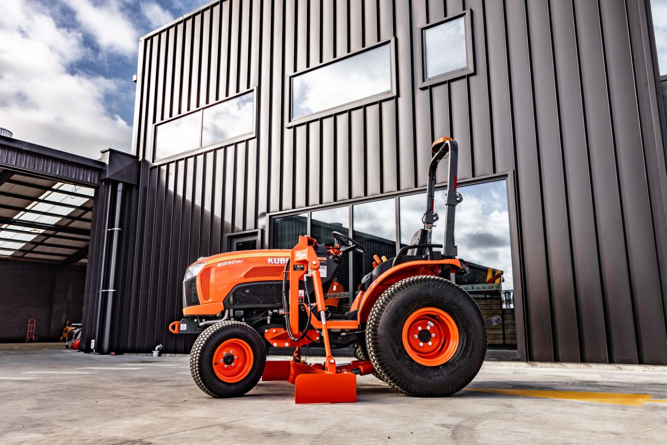 Side view of small orange tractor grader
