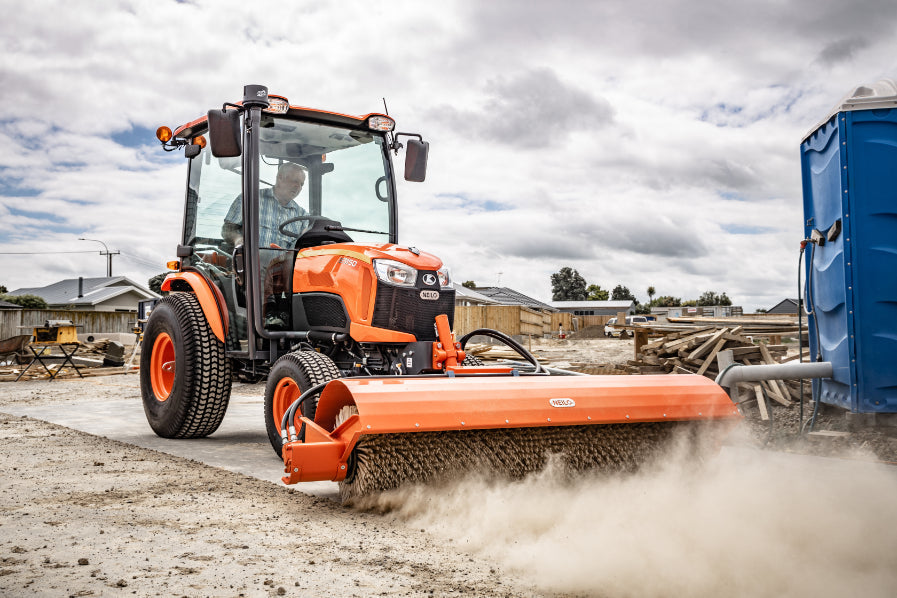 Orange Kubota B3150 Tractor with large Neilo Broom at a construction site